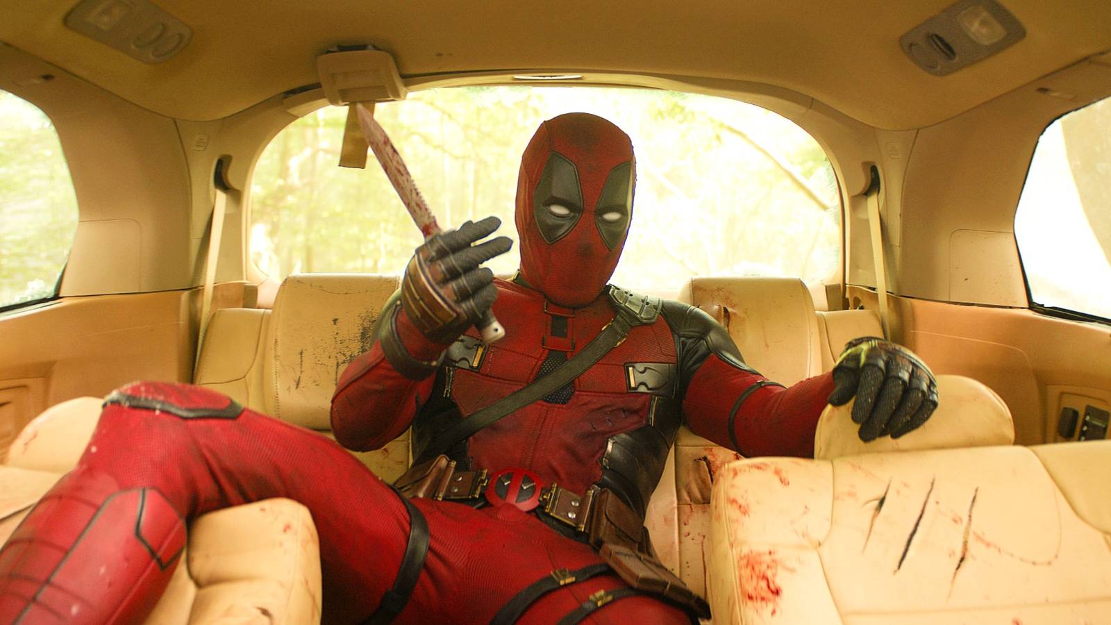 ryan-reynolds-as-deadpool-sprawled-in-the-backseat-of-a-car-covered-in-bloody-scratches-in-deadpool.jpeg