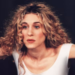 Best Series Premiering Each Year of the Decade carrie-bradshaw-sarah-jessica-parker-looking-out-her-apartment-window-for-a-sex-and-the-city-publici.avif