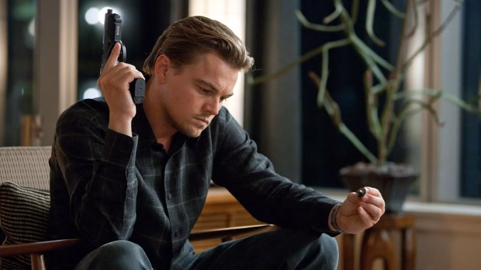 leonardo-dicaprio-as-dom-cobb-holding-a-gun-and-the-spinning-top-in-inception.jpg