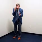 tim-robinson-standing-in-a-white-room-holding-a-phone-to-his-ear-in-the-chair-company.jpg